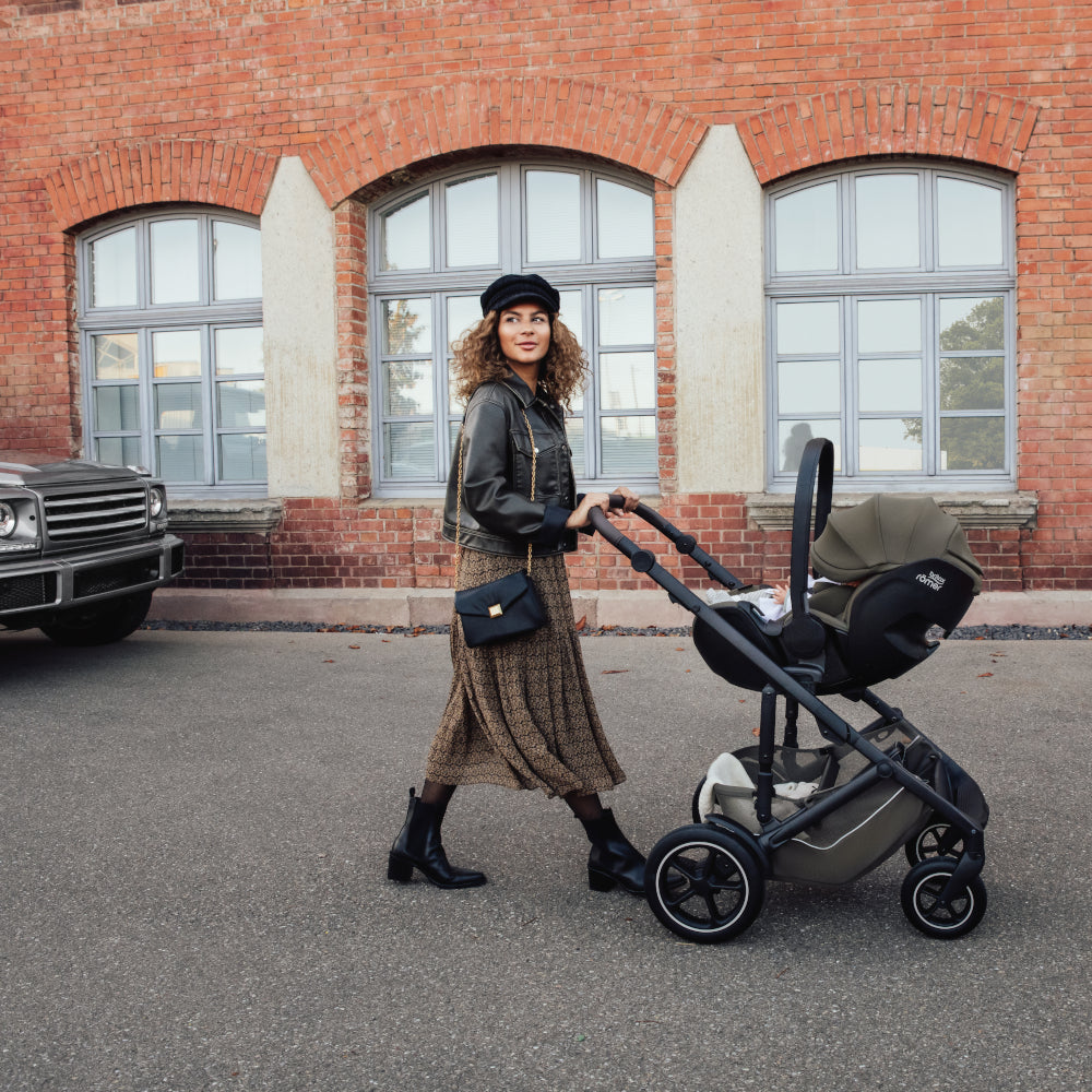 Mum pushing baby in Britax-Römer Baby-Safe Pro infant carrier car seat in Urban Olive, on Smile III pushchair