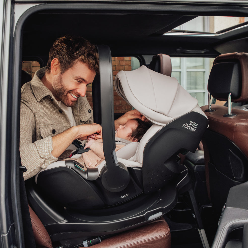 Dad in car with baby in Britax-Römer Baby-Safe Pro infant carrier car seat in Warm Caramel on Vario 5Z ISOfix base