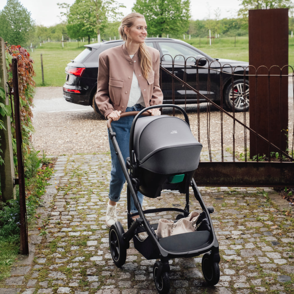 Britax Römer Baby-Safe Core infant carrier car seat in midnight grey, mum pushing Smile III pushchair