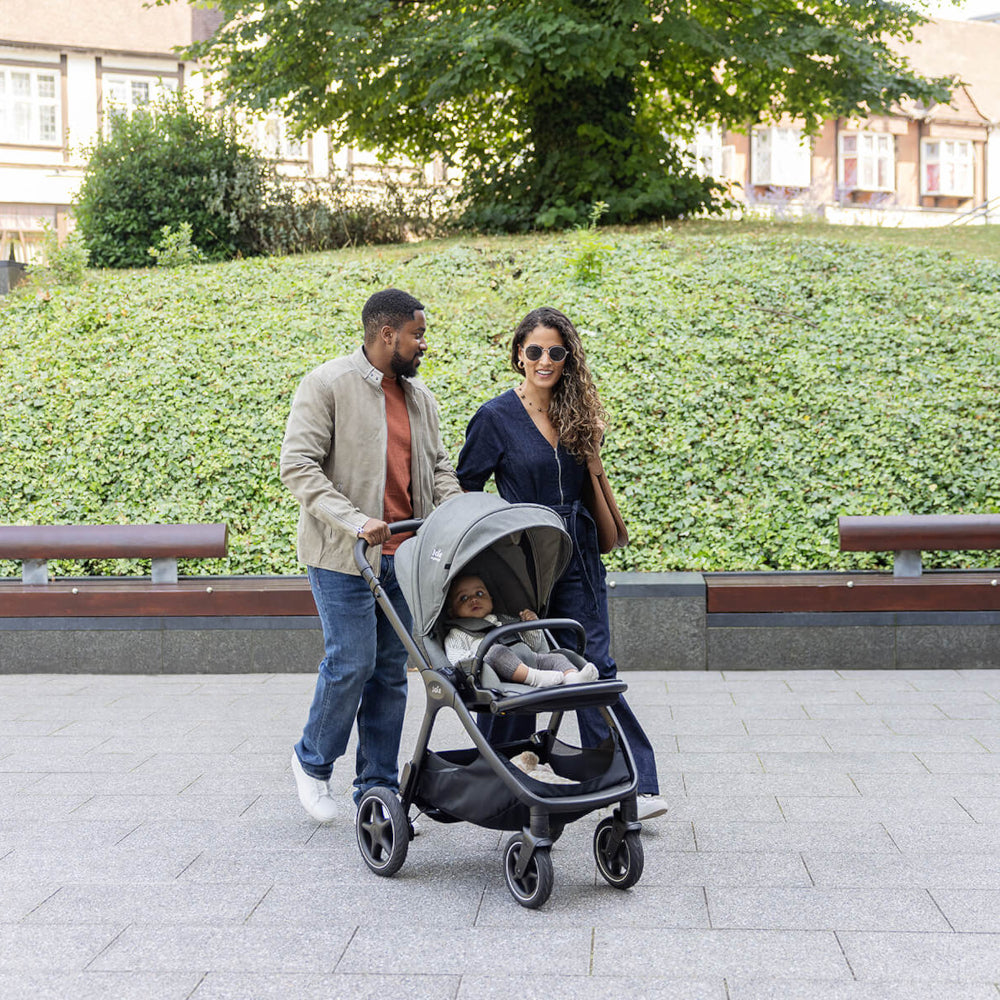 Couple pushing baby in Joie Finiti Pushchair Evergreen