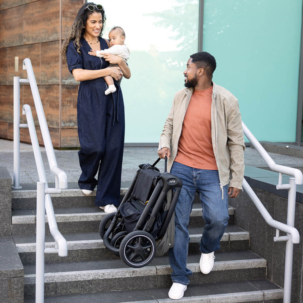 Family with a baby and a Joie Finiti stroller walking down steps outdoors.